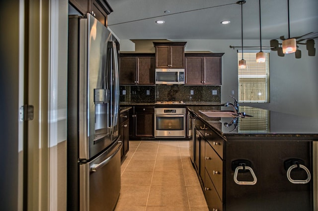 3418 El Molino, Clovis, CA 93619 - kitchen with stainless steel appliances, backsplash, a center island with sink, dark brown cabinetry, and light tile patterned flooring