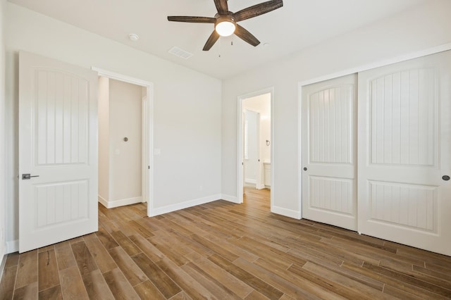 unfurnished bedroom with a closet, visible vents, baseboards, and wood finished floors
