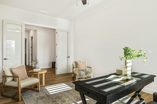 interior space with baseboards, wood finished floors, and a ceiling fan