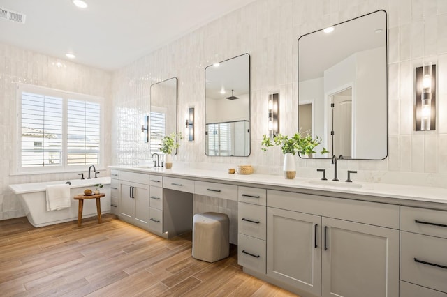 full bathroom with visible vents, tile walls, wood finished floors, and a sink