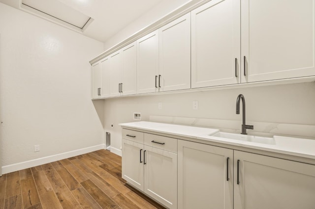laundry room with a sink, cabinet space, light wood finished floors, baseboards, and hookup for a washing machine
