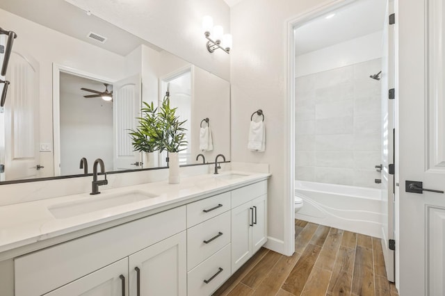 bathroom featuring toilet, wood finished floors, visible vents, and a sink