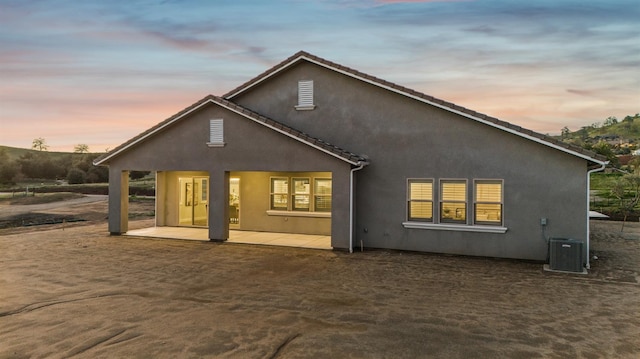 back of house with stucco siding, a patio, and central AC unit