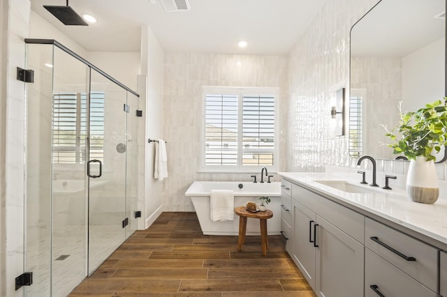 full bathroom featuring vanity, wood tiled floor, a soaking tub, a shower stall, and tile walls