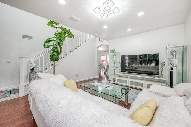 living room featuring visible vents, baseboards, stairs, wood finished floors, and arched walkways