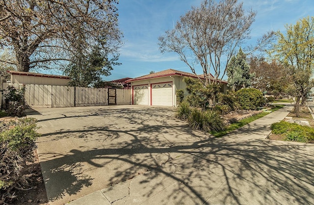 view of side of property featuring stucco siding, fence, driveway, and a garage
