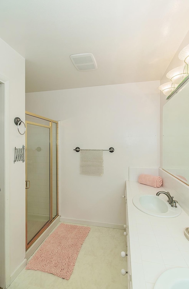 bathroom with baseboards, a sink, double vanity, and a stall shower