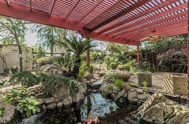 exterior space with a garden pond, a pergola, a fenced backyard, and a ceiling fan