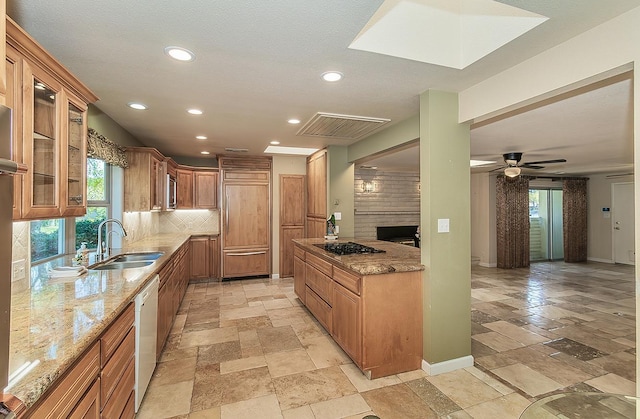 kitchen featuring stone tile floors, a healthy amount of sunlight, light stone counters, and a sink