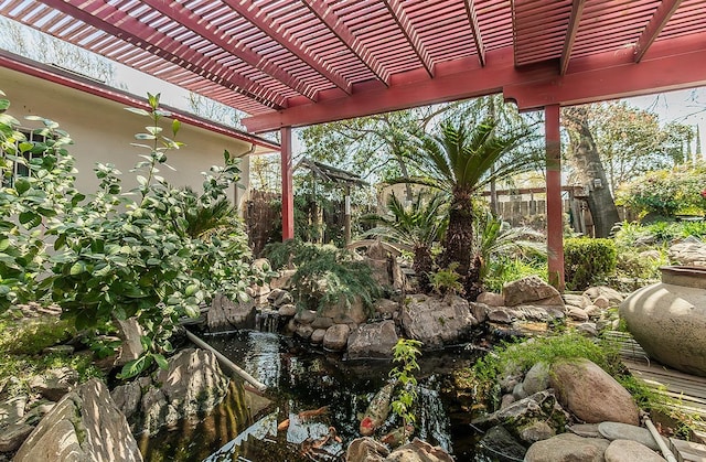 view of yard with a small pond, a pergola, and fence