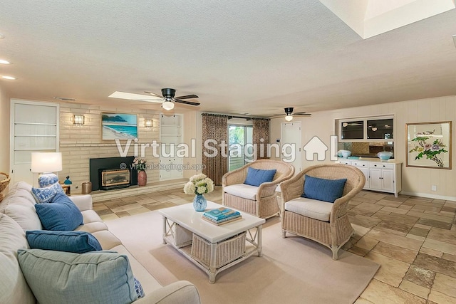 411 W Vartikian Ave W, Fresno, CA 93704 - living room featuring ceiling fan, a brick fireplace, stone tile floors, a textured ceiling, and a skylight