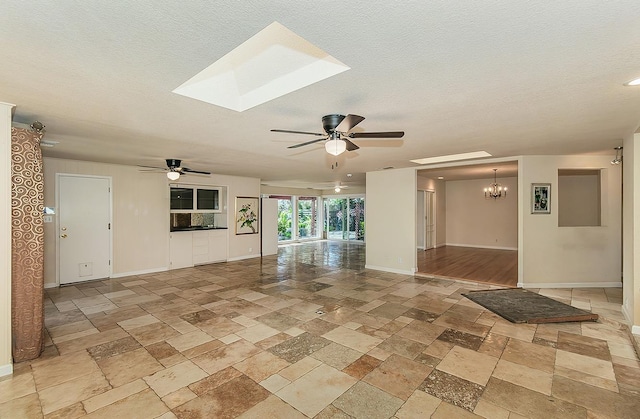 411 W Vartikian Ave W, Fresno, CA 93704 - empty room featuring a ceiling fan, stone tile floors, baseboards, a skylight, and a textured ceiling