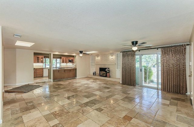 unfurnished living room with stone tile flooring, visible vents, and a ceiling fan