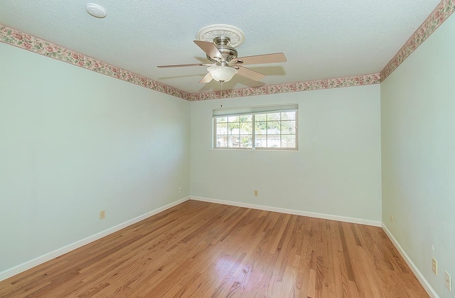 empty room featuring ceiling fan, baseboards, a textured ceiling, and light wood-style flooring