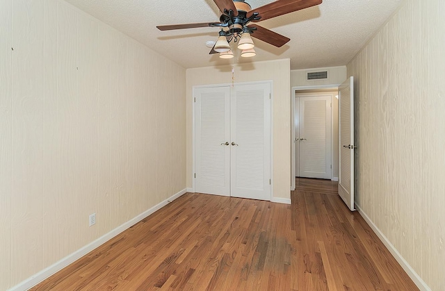 unfurnished bedroom with wood finished floors, visible vents, and a closet