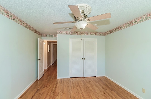 unfurnished bedroom with a textured ceiling, a closet, light wood-type flooring, baseboards, and visible vents