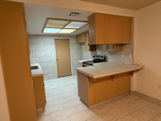 2512 Driftwood Dr, Madera, CA 93637 - kitchen featuring light countertops, a breakfast bar, stainless steel range with electric cooktop, visible vents, and a peninsula