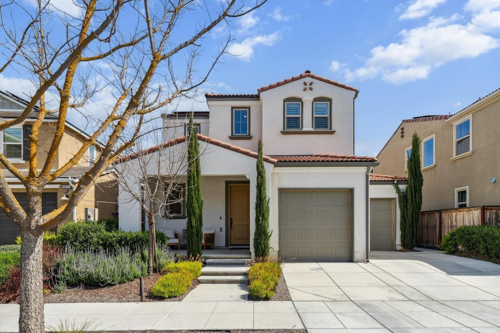 mediterranean / spanish home featuring stucco siding, a tile roof, concrete driveway, and an attached garage