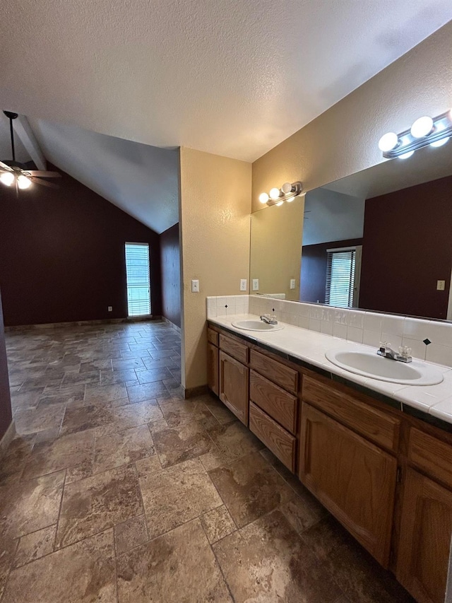 18149 Varden Dr, Madera, CA 93638 - full bathroom featuring vaulted ceiling, stone tile flooring, a sink, and a textured ceiling