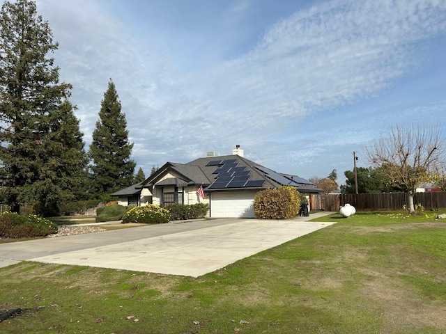 18149 Varden Dr, Madera, CA 93638 - ranch-style house featuring a chimney, fence, a front lawn, roof mounted solar panels, and a garage