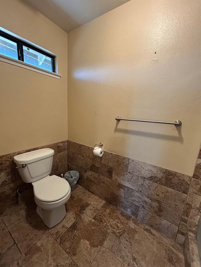 18149 Varden Dr, Madera, CA 93638 - bathroom with tile walls, toilet, stone tile flooring, and wainscoting