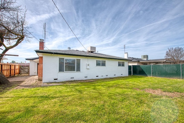 back of property with a lawn, crawl space, a chimney, and a fenced backyard