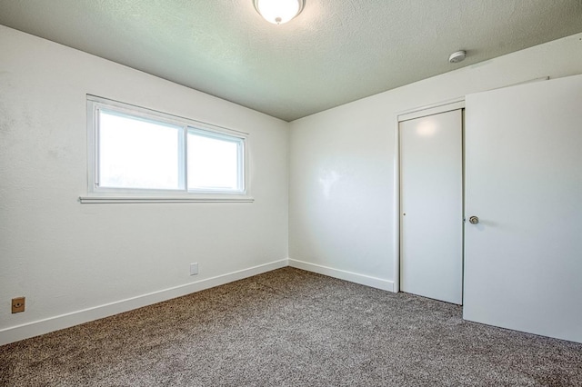 carpeted empty room with baseboards and a textured ceiling