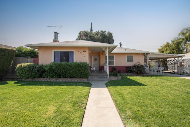 view of front of house with fence, a front lawn, an attached carport, and stucco siding