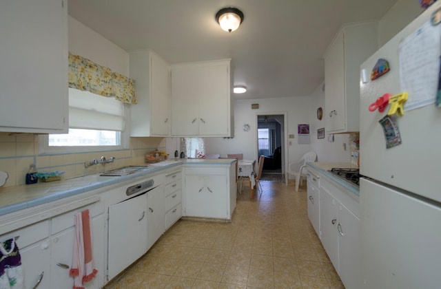 kitchen featuring white cabinets, tile countertops, light tile patterned floors, freestanding refrigerator, and decorative backsplash