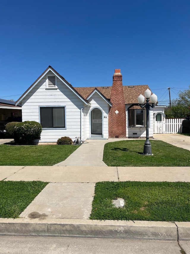 view of front of property with a chimney, fence, and a front lawn