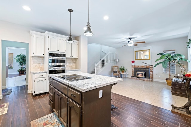 1110 Minarets Ave, Clovis, CA 93611 - kitchen with black electric stovetop, white cabinets, double oven, a ceiling fan, and baseboards