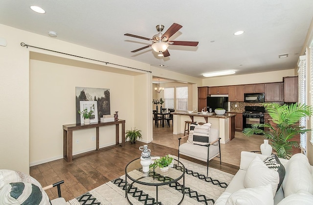living area featuring a ceiling fan, light wood-style floors, baseboards, visible vents, and recessed lighting