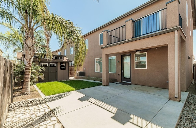 back of property featuring a balcony, a shed, central air condition unit, a patio, and stucco siding
