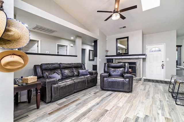 living area with a ceiling fan, wood finished floors, lofted ceiling, and visible vents