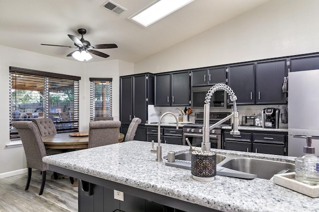 kitchen with freestanding refrigerator, lofted ceiling, light wood-style flooring, visible vents, and ceiling fan