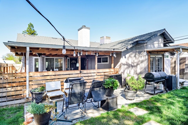 rear view of property with fence, a chimney, a shingled roof, and a patio
