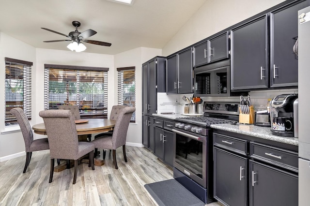 kitchen featuring light wood-style flooring, baseboards, stainless steel appliances, a ceiling fan, and tasteful backsplash