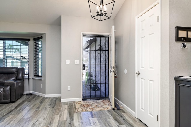 foyer with a notable chandelier, baseboards, and wood finished floors