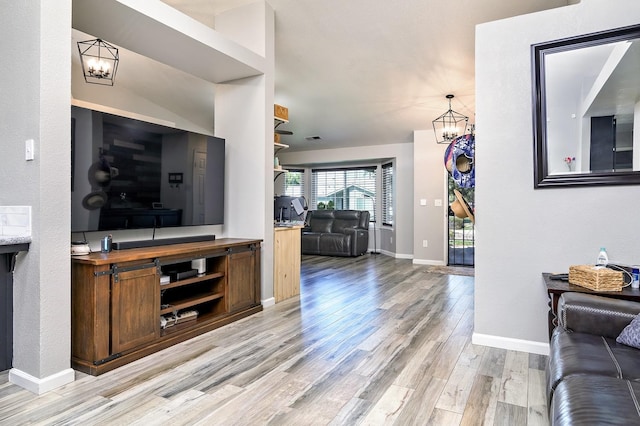 living area with an inviting chandelier, visible vents, baseboards, and light wood-type flooring