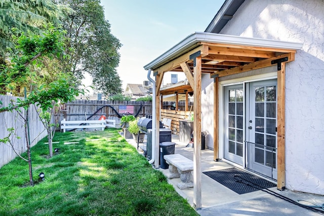 view of yard featuring french doors, a fenced backyard, and a patio
