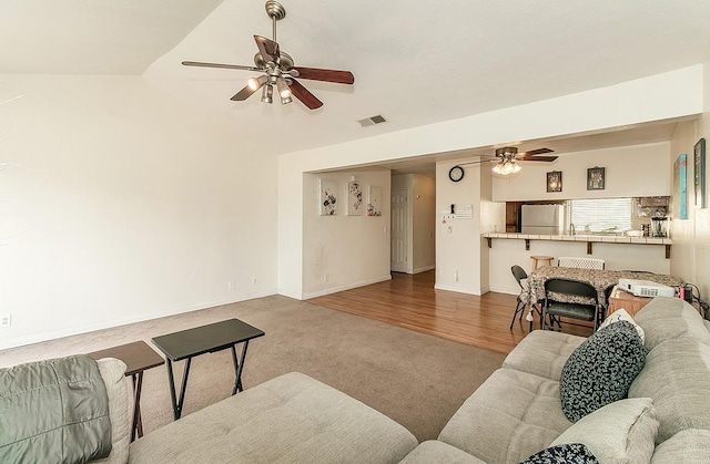 living area featuring visible vents, carpet flooring, baseboards, a ceiling fan, and vaulted ceiling