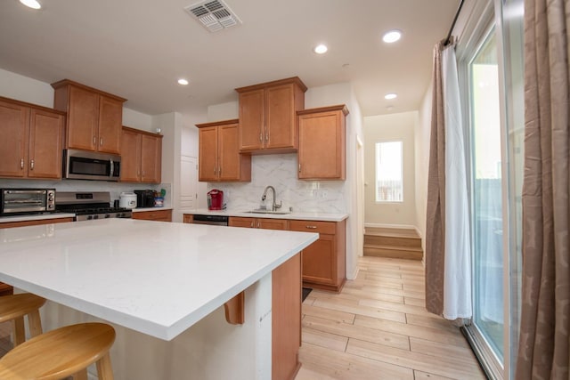 4865 E Alexander Ave, Fresno, CA 93725 - kitchen featuring stainless steel appliances, a kitchen bar, light countertops, tasteful backsplash, and a center island