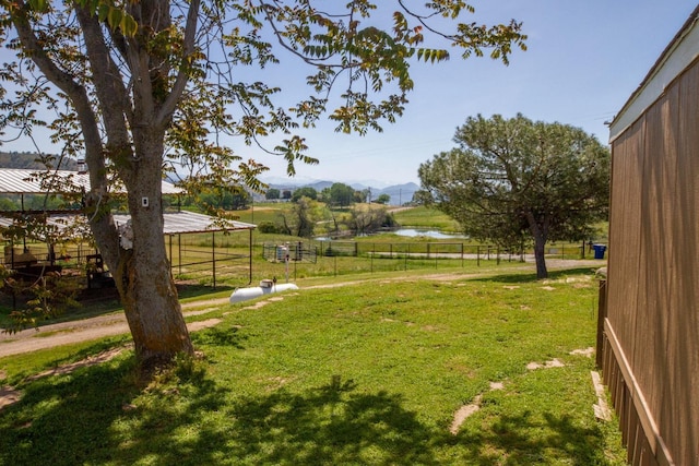 view of yard featuring fence, a mountain view, and a rural view