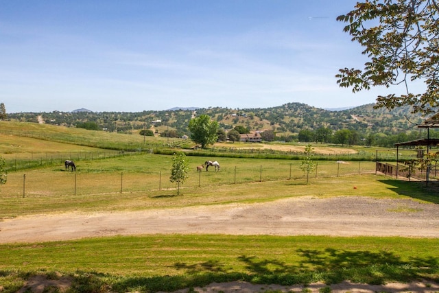 view of yard featuring a mountain view, fence, and a rural view