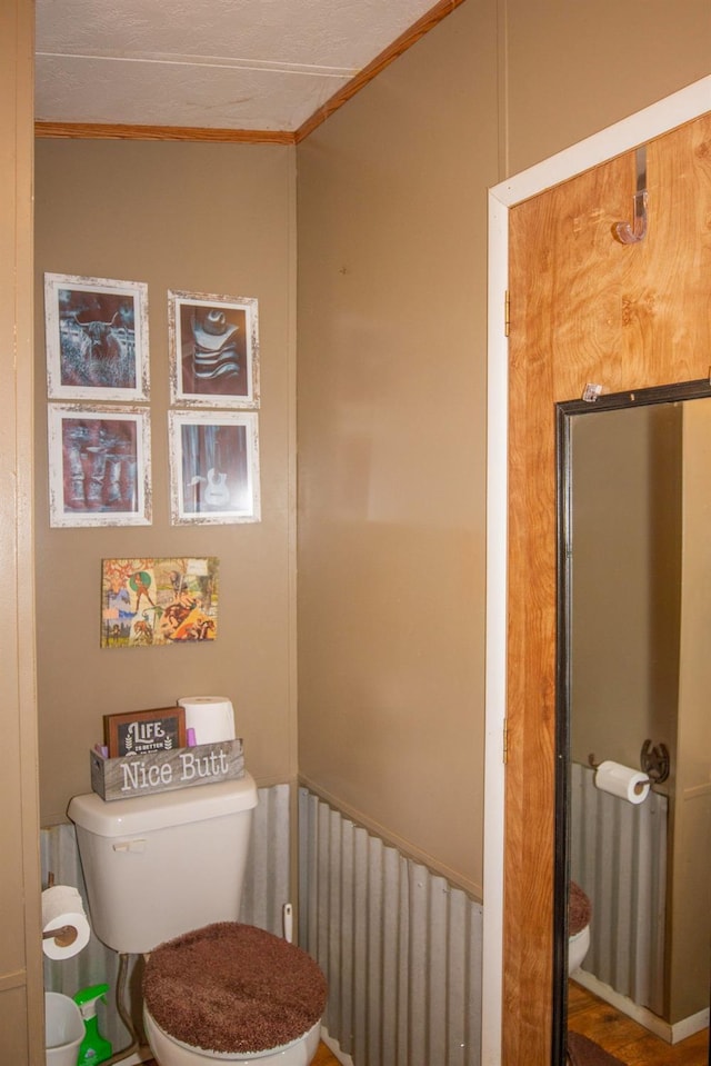 bathroom with radiator heating unit, crown molding, and toilet