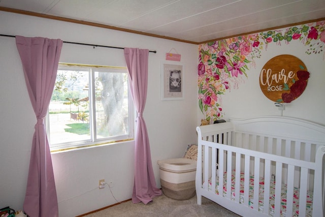 bedroom featuring a nursery area, carpet flooring, and crown molding