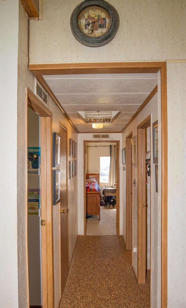 corridor with ornamental molding, visible vents, and carpet