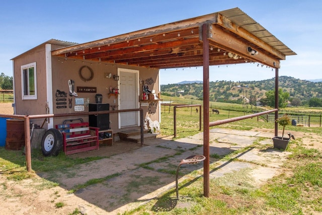 exterior space with a rural view, a carport, entry steps, and a mountain view