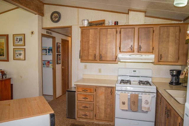 kitchen with light countertops, exhaust hood, vaulted ceiling, and gas range gas stove