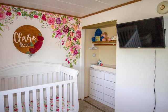 bedroom with a crib, ornamental molding, and carpet floors